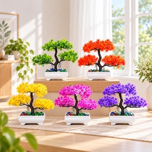 May include: Five artificial bonsai trees in white rectangular pots, each featuring a dark brown trunk and vibrant plastic foliage in green, orange, yellow, pink, and purple, with colorful glass pebbles covering the soil surface.