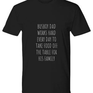 May include: Black t-shirt with white text that reads "Busboy Dad Works Hard Every Day To Take Food Off The Table For His Family."