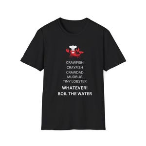 May include: A black short-sleeved t-shirt featuring a graphic of a red crawfish wearing a white chef hat. Below the graphic, the text reads: CRAWFISH, CRAYFISH, CRAWDAD, MUDBUG, TINY LOBSTER, WHATEVER! BOIL THE WATER, all printed in white capital letters.