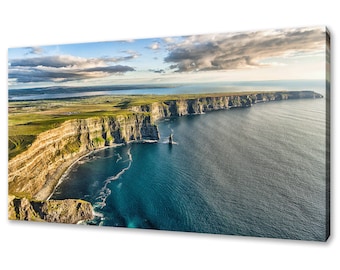 May include: An aerial view of the Cliffs of Moher in Ireland. The cliffs are a dramatic natural landmark, with towering rock faces that rise up from the Atlantic Ocean. The sky is a bright blue, with fluffy white clouds.