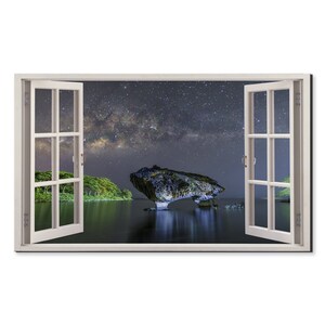 May include: A window view of a large rock formation in the water with a starry night sky and the Milky Way visible. The rock formation is illuminated by the light of the stars.