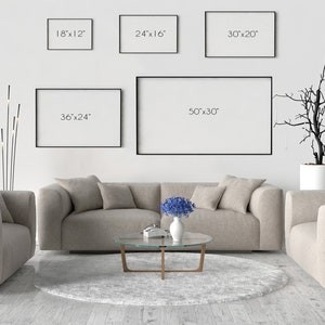 May include: A living room interior with a white wall, a beige sofa, two armchairs, a glass coffee table, a floor lamp, and a potted tree. There are five black picture frames on the wall with the dimensions 18"x12", 24"x16", 30"x20", 36"x24", and 50"x30" written on them.