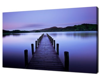 May include: A wooden jetty stretches out into a tranquil lake at dusk. The water is a soft purple hue, and the sky is a pale blue. The jetty is made of weathered wood and has a rustic appearance.