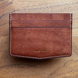 Portefeuille signature M+B coupé en V en veau pueblo cognac. Porte-cartes luxueux et unique avec 5 emplacements pour cartes. Un transport quotidien minimaliste et élégant.