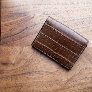 Portafoglio bi-fold petite con 4 scomparti per cc. Alligatore color cognac abbinato a pelle di capra blu Lazuli, edc minimalista di lusso.
