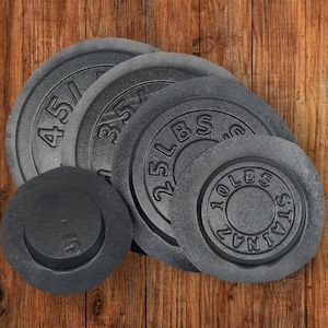 Puede incluir: Cuatro placas de peso de hierro fundido gris con los siguientes pesos: 45 libras, 35 libras, 25 libras y 10 libras. Las placas est&aacute;n apiladas unas sobre otras.
