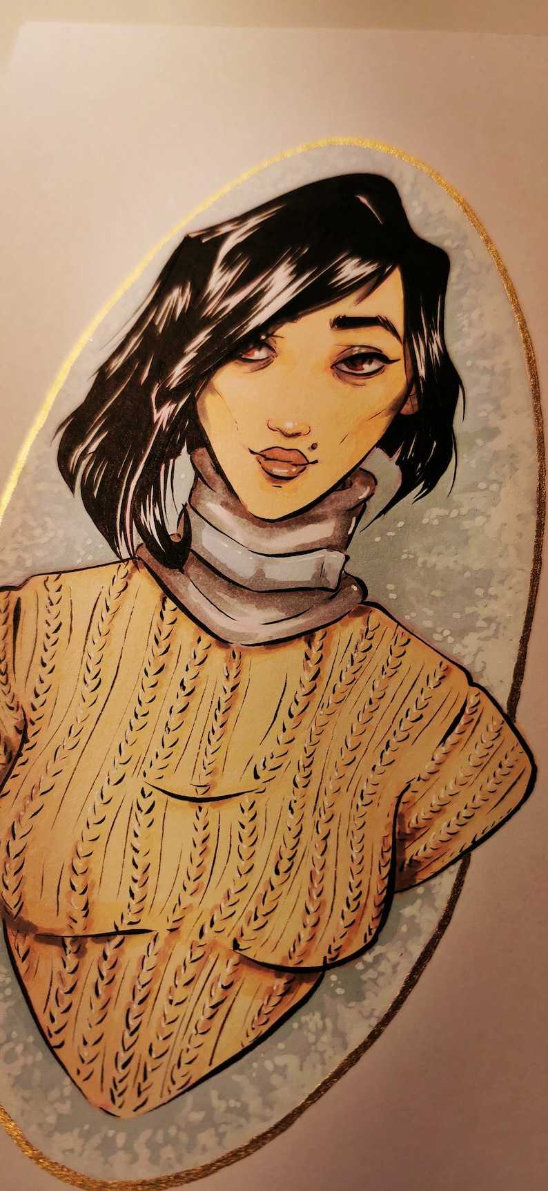 May include: A hand-drawn illustration of a woman with dark hair wearing a brown knitted sweater and a white turtleneck. The illustration is set against a light blue background with gold accents.