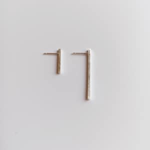 Può includere: Un paio di orecchini a barra in argento. Gli orecchini sono semplici e minimalisti, con una finitura spazzolata.