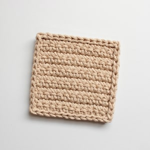 May include: A square beige crocheted coaster. The coaster is made with a simple stitch pattern and has a slightly textured surface.