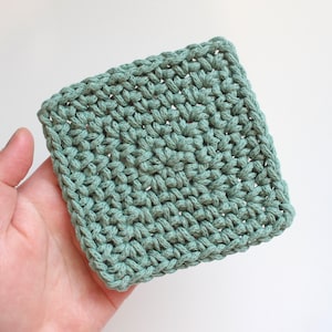 May include: A square crocheted coaster in a light green color. The coaster is made with a simple stitch pattern and has a slightly textured surface.
