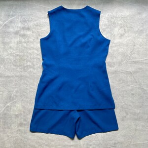 Op de afbeelding: Een blauwe, mouwloze jurk met een bijpassend short. De jurk heeft een simpel ontwerp en een licht uitlopende rok.