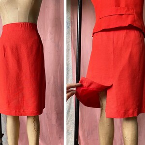 May include: A bright red skirt suit with a straight skirt and a fitted jacket. The skirt has a centre back seam and the jacket has a single button closure.