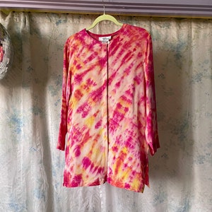 May include: A pink and yellow tie-dye long-sleeved shirt with a button-up front.