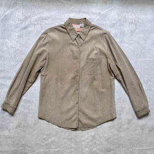 May include: A long-sleeved, button-down shirt in a light brown color. The shirt has a single chest pocket and a brand label on the collar.