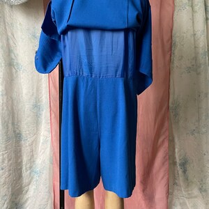 Op de afbeelding: Een koninklijk blauwe jumpsuit met korte mouwen en een transparante overlay op de rug.