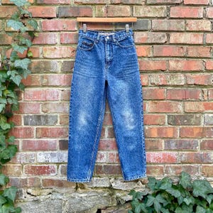 Op de afbeelding: Een paar blauwe denim jeans met een ontspannen pasvorm en een hoge taille. De jeans heeft een vervaagde wassing en een lichtblauwe kleur.
