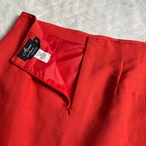 May include: A red skirt with a zip at the back. The skirt has a black label that says "Alena" and "cotton/spandex" with a size tag that says "12".