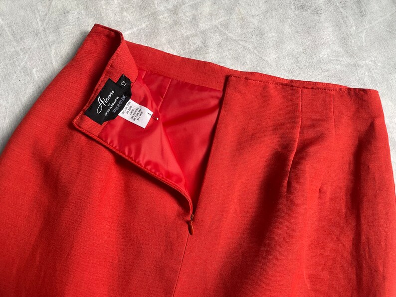May include: A red skirt with a zip at the back. The skirt has a black label that says "Alena" and "cotton/spandex" with a size tag that says "12".