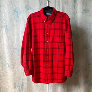May include: A red and black plaid flannel shirt with a button-down collar and long sleeves.