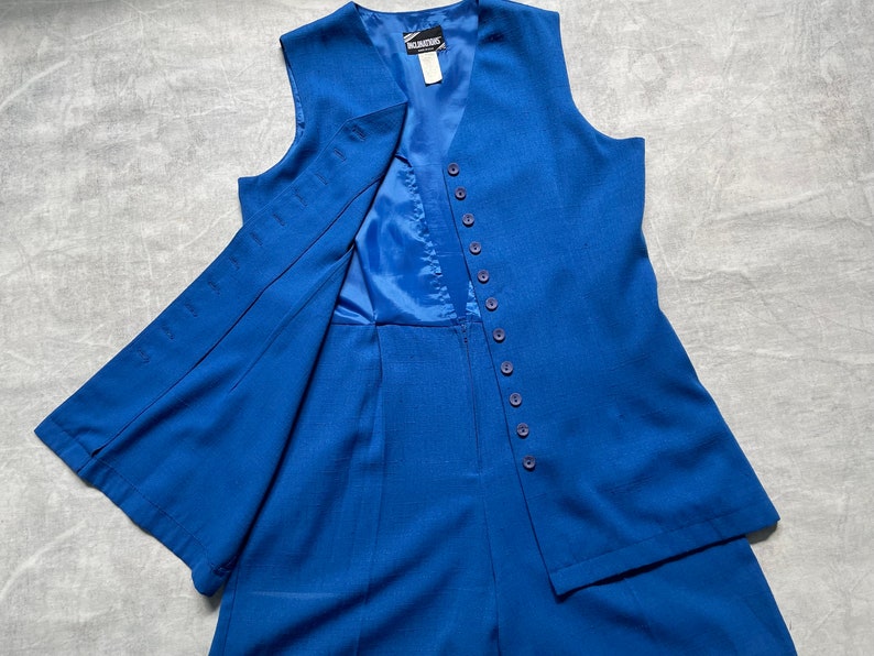 Op de afbeelding: Een koninklijk blauwe, mouwloze vest en bijpassende shorts set met een knoopsluiting. De vest heeft een V-hals en de shorts hebben een rechte pijp.