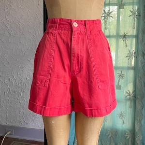 May include: A pair of high-waisted, red, cuffed shorts with two large pockets on the front.