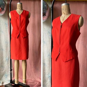 May include: A red sleeveless dress with a zip down the front and a fitted skirt. The dress is on a mannequin.