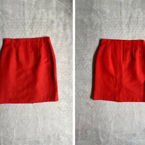 May include: A red mini skirt with a straight cut and a zip at the back.