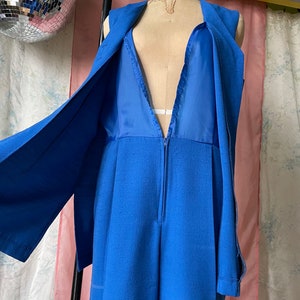Op de afbeelding: Een mouwloze jumpsuit in een levendige blauwe kleur. De jumpsuit heeft een diepe V-hals en een ritssluiting aan de voorkant. De stof lijkt een linnenmix te zijn.