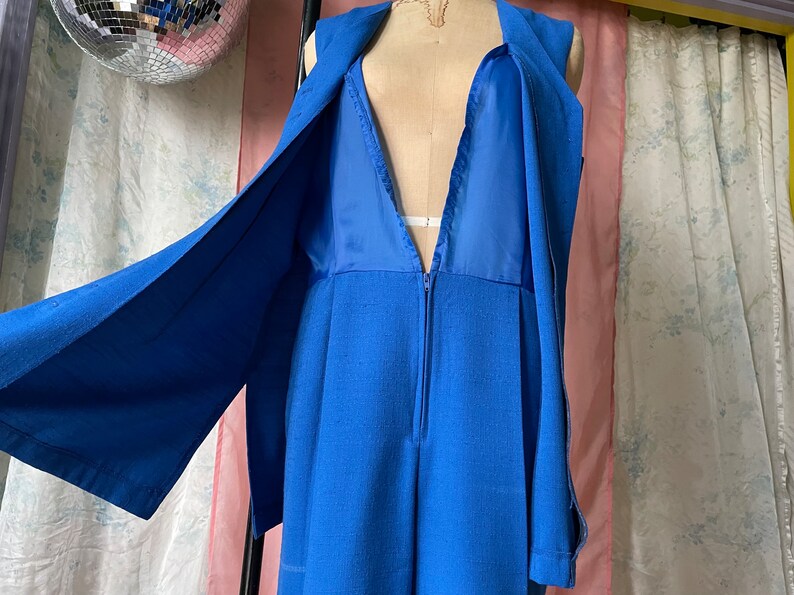 Op de afbeelding: Een mouwloze jumpsuit in een levendige blauwe kleur. De jumpsuit heeft een diepe V-hals en een ritssluiting aan de voorkant. De stof lijkt een linnenmix te zijn.