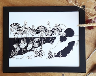 May include: Black and white paper cut art print of a woman lying in a pond with lily pads and fish. The print is framed in a black frame.