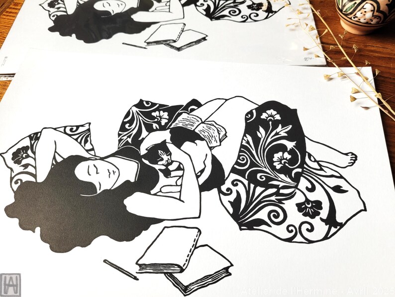 May include: Black and white illustration of a person reclining with a cat, reading a book. The person is surrounded by pillows and a patterned blanket. Two books and a pencil are also visible.