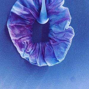 May include: A purple and blue tie-dye scrunchie made of fabric.