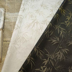 May include: Close-up of three fabric samples with a bamboo leaf pattern. The fabrics are in cream, off-white, and dark brown. The bamboo leaves are in a metallic gold colour. The fabrics are likely for home decor or fashion.