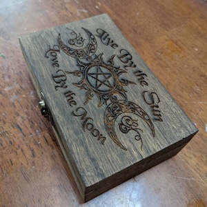 May include: A handmade wooden sign with the word "Welcome" in a playful font. The sign has a distressed white background and a dark stained wooden frame. A decorative floral element is in the corner.