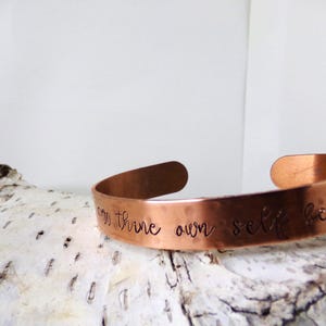 May include: A copper bracelet with the inscription "Be thine own self be true".