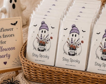 May include: A wicker basket filled with rectangular packets of wildflower seeds, each featuring a ghost wearing a purple beanie and holding a mug labeled BOO with the text Stay Spooky. A sign reads Wildflower seeds favors for Halloween party.