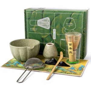 May include: A matcha set with a green ceramic bowl, whisk, whisk holder, scoop, sifter, and a decorative mat. The box features illustrations of the whisk and holder. The set includes a bamboo whisk and a ceramic bowl.