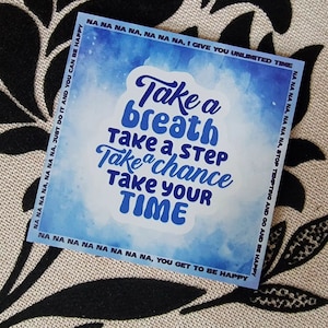 Op de afbeelding: Blauwe en witte aquarel achtergrond met de tekst "Take a breath, Take a step, Take a chance, Take your time" in blauwe letters. De tekst wordt omringd door een blauwe rand met de woorden "NA NA NA NA, NA NA NA, JUST DO IT AND YOU CAN BE HAPPY" en "NA NA NA NA, NA NA NA, STOP TEMPTING AND GO AND BE HAPPY" aan de linker- en rechterkant van de afbeelding.