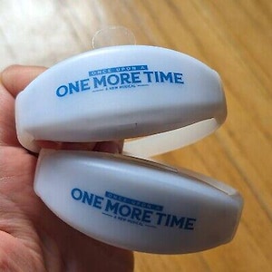 Può includere: Due braccialetti di plastica bianchi con testo blu che recita "Once Upon A Time - A New Musical - One More Time".