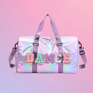 May include: A purple iridescent duffel bag with a zipper closure and adjustable shoulder strap. The bag has the word "DANCE" in colorful letters on the front.