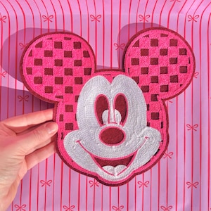 May include: Pink and white embroidered Mickey Mouse character patch with a checkered pattern on the ears.