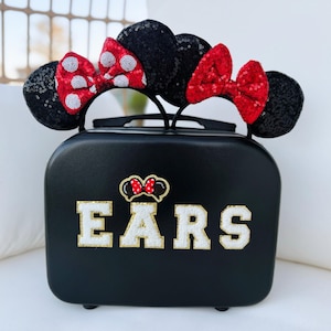 May include: Black suitcase with a white "EARS" design and two red and white Minnie Mouse ears on top.