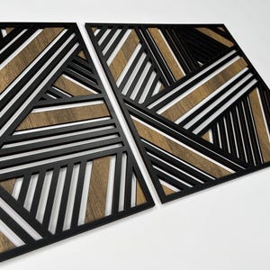 May include: Two black geometric wall panels with a wood grain pattern. The panels are made of wood and have a modern design.