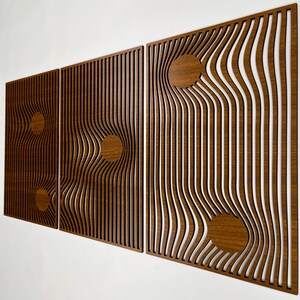 May include: Three wooden wall panels with a unique design. Each panel features a series of vertical lines that curve and bend, creating a wave-like effect. Circular wooden accents are incorporated into the design, adding visual interest. The panels are a warm brown color.