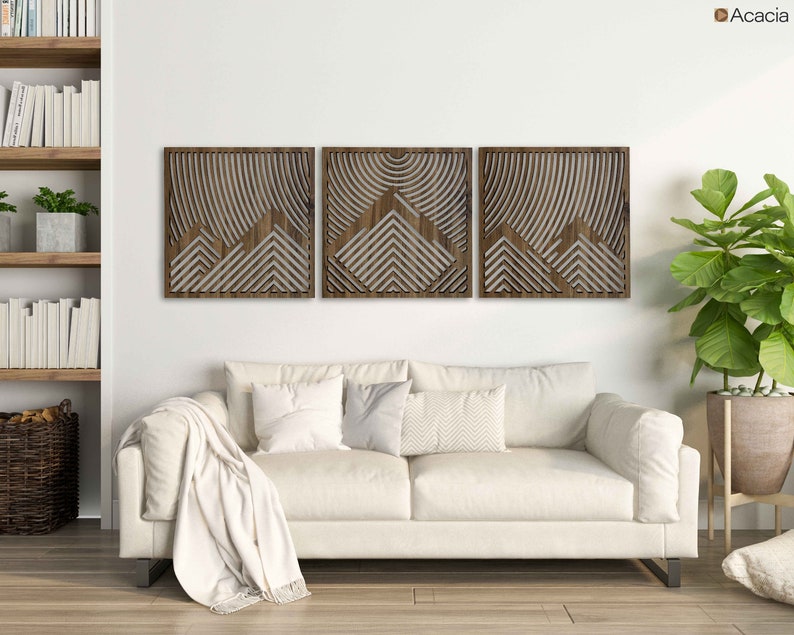 May include: Three wooden wall panels with a geometric design of overlapping triangles and lines. The panels are made of acacia wood and have a natural brown finish.