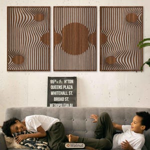 May include: Three walnut wood wall panels with a wave-like design and circular cutouts. The panels are mounted above a grey sofa. The text on the sign reads "95th St. F. H'ton Queens Plaza Whitehall St. Broad St. Metropolitan Av."