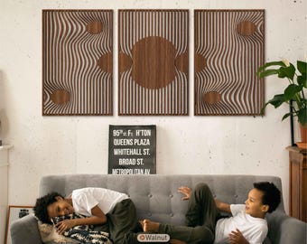 May include: Three walnut wood wall panels with a wave-like design and circular cutouts. The panels are mounted above a gray sofa. The text on the sign reads "95th St. F. H'ton Queens Plaza Whitehall St. Broad St. Metropolitan Av."