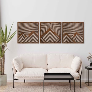 May include: Three wooden wall panels with a geometric mountain design. The panels are in a walnut finish and are arranged in a row on a white wall.
