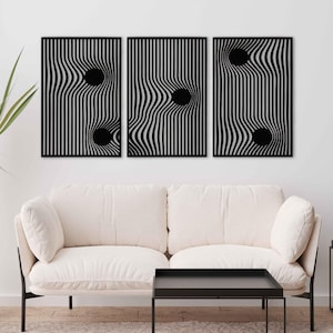 May include: Three black wall art panels with a wavy, striped design and a black circular element. The artwork is displayed above a white sofa and black coffee table, creating a modern aesthetic. The panels are a decorative element.