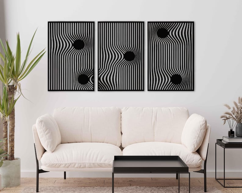 May include: Three black wall art panels with a wavy, striped design and a black circular element. The artwork is displayed above a white sofa and black coffee table, creating a modern aesthetic. The panels are a decorative element.